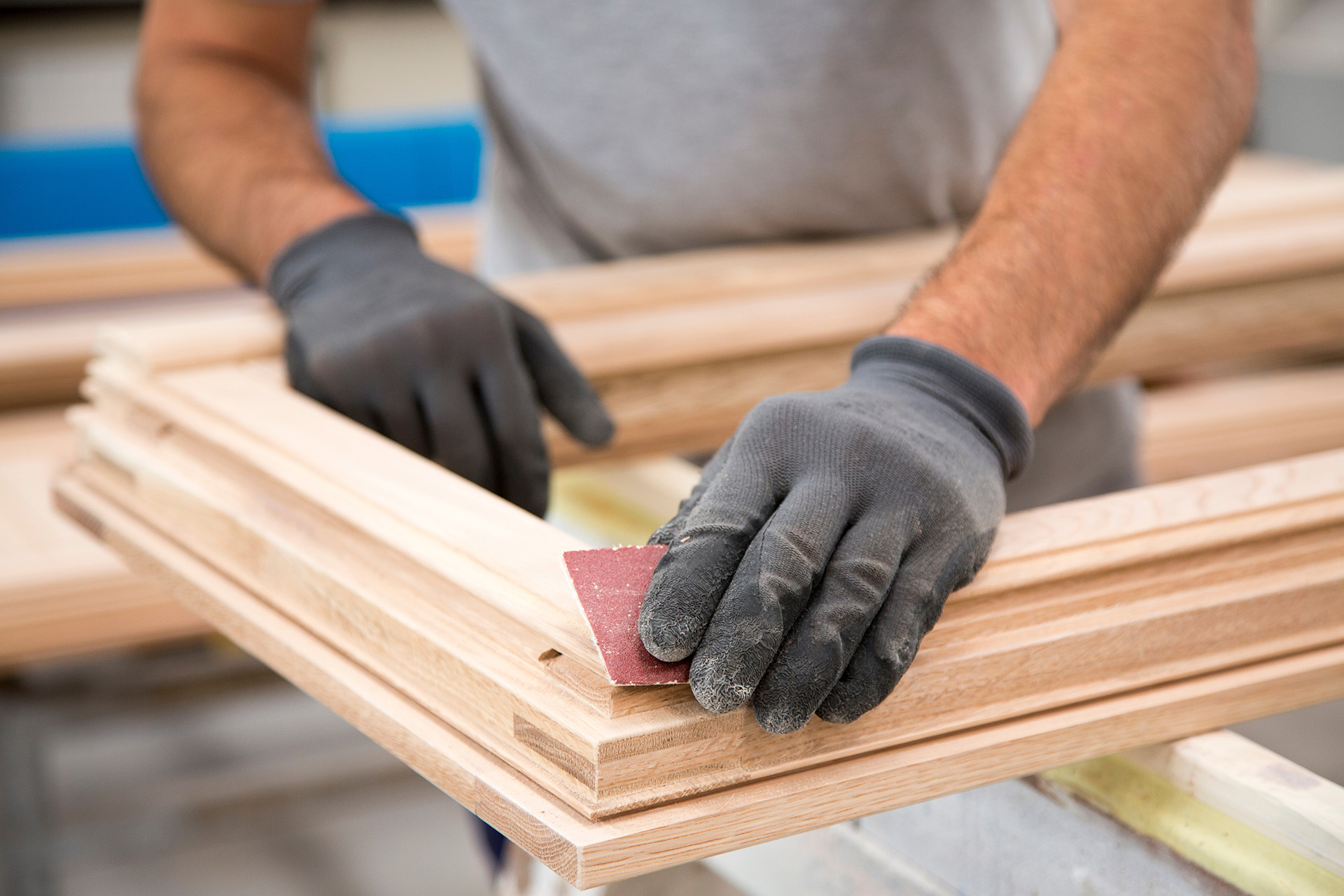 Ein Fensterbauer schleift am Holzrahmen und ist versichert über die Global Brokerservices